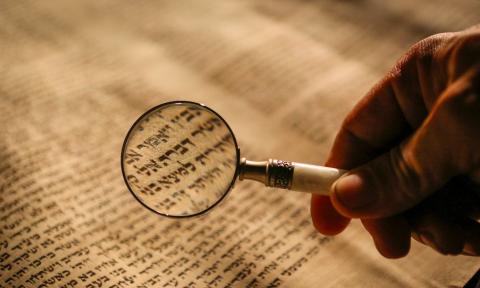 Magnifying glass over Hebrew text.